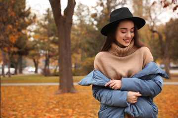 Wall Mural - Young woman wearing stylish clothes in autumn park, space for text