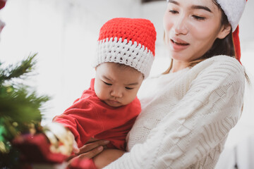 Wall Mural - merry christmas and happy Holidays. mother held her daughter near the christmas tree and decorate the christmas tree indoors. the morning before Xmas. Portrait loving family close up.