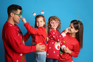 Sticker - Family in Christmas sweaters and festive accessories having fun on blue background