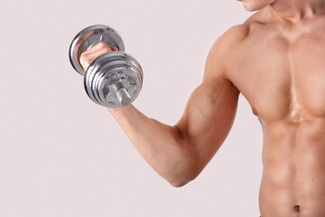Wall Mural - Cropped view of strong millennial sportsman with sexy body lifting dumbbell on light studio background, copy space