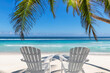 Paradise beach with white sand and beach chairs in shadow of coco palms. Summer vacation and tropical beach concept.	