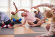 © Monkey Business - Group With Teacher Sitting On Exercise Mats Stretching In Yoga Class Inside Community Center