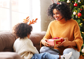 Cheerful ethnic family: happy child and mother congratulate each other at Christmas