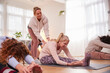 © Monkey Business - Teacher Helping Group Stretching On Exercise Mats In Yoga Or Fitness Class Inside Community Center