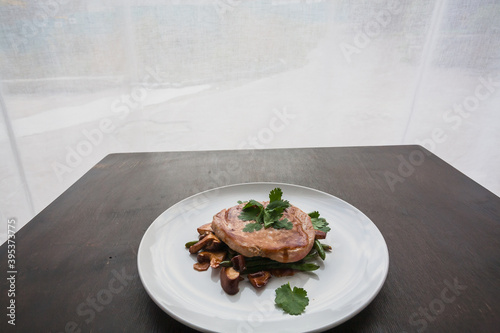 Fotografía Plate with cooked steak and mushrooms inside a restaurant