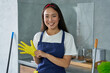 © Friends Stock - For a clean house. Portrait of joyful young woman, cleaning lady smiling at camera, wearing protective glove while getting ready for cleaning the house