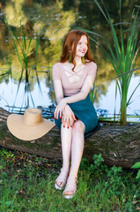 Close up portrait of a beautiful red hair girl in a pink vintage dress and straw hat standing near colorful flowers. Art work of romantic woman .Pretty tenderness model looking at camera.