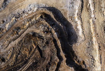 Working quarry environment seen from a drone. Amazing colorful patterns created by heavy machinery in the mine. An active quarry at aerial photo from a drone. Aggregate piles and steep quarry walls