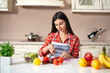 girl at the kitchen table cuts vegetables and fruits