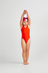 little child girl in swimsuit, swimming goggles and swim cap is preparing for swimmin. Full length. child dreams of becoming a swimming champion