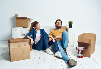 Man and woman in the room on the floor renovation work moving and boxes of tools