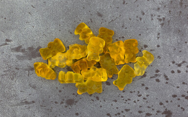 Wall Mural - Colorful yellow gummi bear sugar candies on a gray background top view.