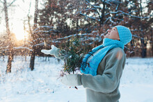 Winter Seasonal Activities. Senior Woman Throwing Snow In The Air At Sunset In Forest Holding Fir Tree Branches