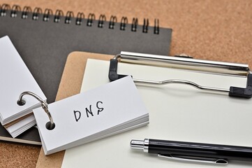 Poster - On top of the notebook and clipboard is a wordbook and pen with the word DNS written on it. It means Domain Name System.