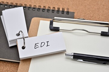 Poster - On top of the notebook and clipboard is a wordbook and pen with the word EDI written on it. It means Electronic Data Interchange.