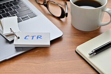 Poster - On a desk with a laptop, glasses, coffee, and a notebook, a vocabulary book was placed open There. The word CTR is there. It's an acronym that means Click Through Rate.