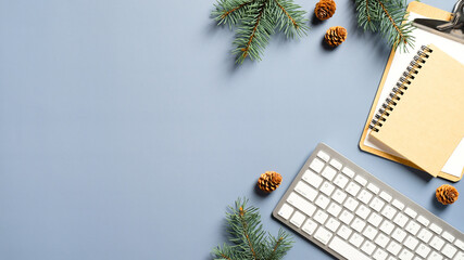 Cozy home desk table with keyboard, notebook, Christmas tree branches, cones on blue background. Top view, flat lay, copy space. Winter composition. Nordic hygge style concept