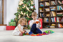Young Girl And Boy Playing With Magnetic Toys Beside Christmas Tree