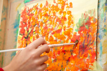 Young Artist Paints Orange Autumn Trees On Canvas