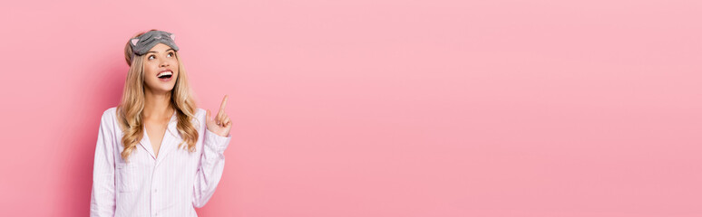 woman in pajamas and blindfold pointing with finger on pink background, banner