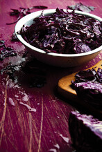 Sliced Red Cabbage In A Bowl With Some Scattered On The Table