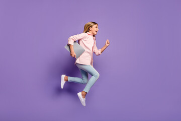 Poster - Full size profile photo of optimistic pretty girl jump run wear pink shirt jeans sneakers hold laptop isolated on violet background