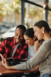 © Jacob Lund - Group of friends sitting at cafe using a phone