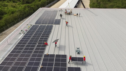 Solar panels installed on a roof of a large industrial building or a warehouse. Industrial buildings in the background. Horizontal photo.