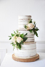 A Naked Three-tier Wedding Cake Decorated With Roses