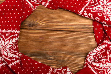 Sticker - top view of winter red knitted scarf on wooden 