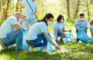 Sticker - volunteering, health and ecology concept - group of volunteers wearing face protective medical masks for protection from virus disease with garbage bags cleaning area in park