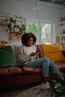 © StratfordProductions - Happy african female relaxing at home browsing and typing on smartphone