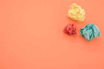 Wall Mural - Top view of green, yellow, and red crumpled papers on orange background