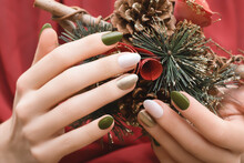 Female Hands With Christmas Nail Design. Green And Gold Nail Polish Manicure. Female Hands Hold New Year Decoration.