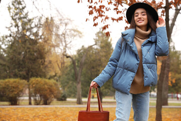 Wall Mural - Young woman wearing stylish clothes in autumn park, space for text