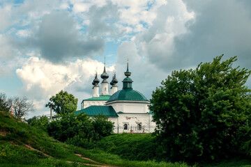 Wall Mural - Ancient Church of the Entrance to Jerusalem and Pyatnitskaya Church, Suzdal. View from the hill in summer on a cloudy day