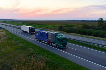 Truck with semi-trailer driving along highway on the sunset background. Goods delivery by roads. Services and Transport logistics. Soft focus.