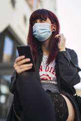 Wall Mural - Selective focus shot of an attractive female wearing a facial mask with a phone in her hands