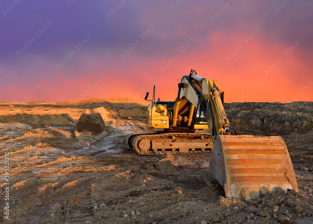 Excavator working on earthmoving at open pit mining on amazing sunset ...