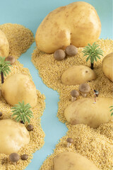 Vertical shot of miniature traveler figure on potato and grain - traveling concept