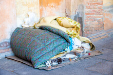 Sleeping Place Of A Homeless Man With Blankets Belongings On The Ground