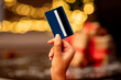 © Home-stock - Female hand with a blue credit card on a Christmas background.