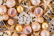 Wooden numbers 2021 on a paper background with shiny golden Christmas balls, glitter stars. Beautiful new year card