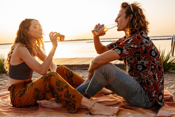 Sticker - Positive young loving couple drinking beer at the beach