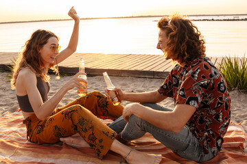 Sticker - Positive young loving couple drinking beer at the beach