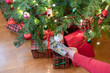 © flowertiare - Woman putting american dollars under red bow of huge gift box lying under christmas tree. Concept