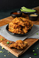 Poster - Vertical shot of delicious fried chicken with sauce and herbs on a wooden board on the table