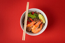 Asian Stir Fry Soba Noodles With Shrimps, Vegetables, Green Peas, Red Pepper In White Bowl With Wooden Chopsticks