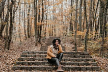 Shot Of A Beautiful Woman Sitting In An Autumn Park