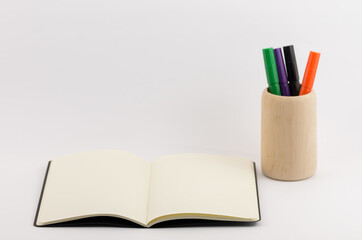 Wall Mural - Closeup shot of an open blank book with a pencil cup isolated on white background